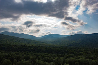A panoramic view of lush green mountains surrounding a rustic eco-lodge at sunrise.