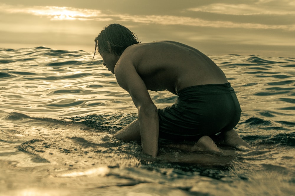 a man kneeling on a surfboard in the ocean
