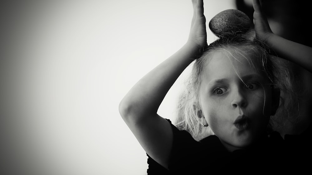 a young girl holding a hair dryer on top of her head