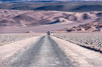 a truck driving down a dirt road in the desert