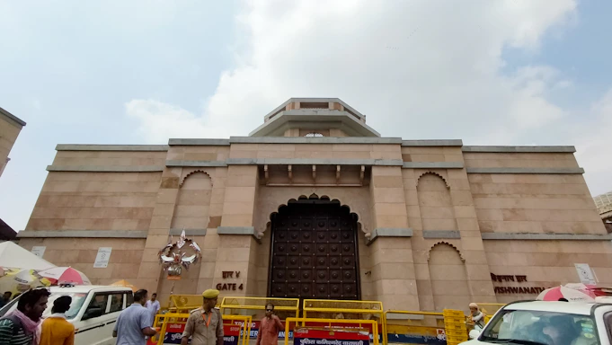 A warm, inviting photo of a friendly tour guide welcoming travelers in front of the Kashi Vishwanath Temple.