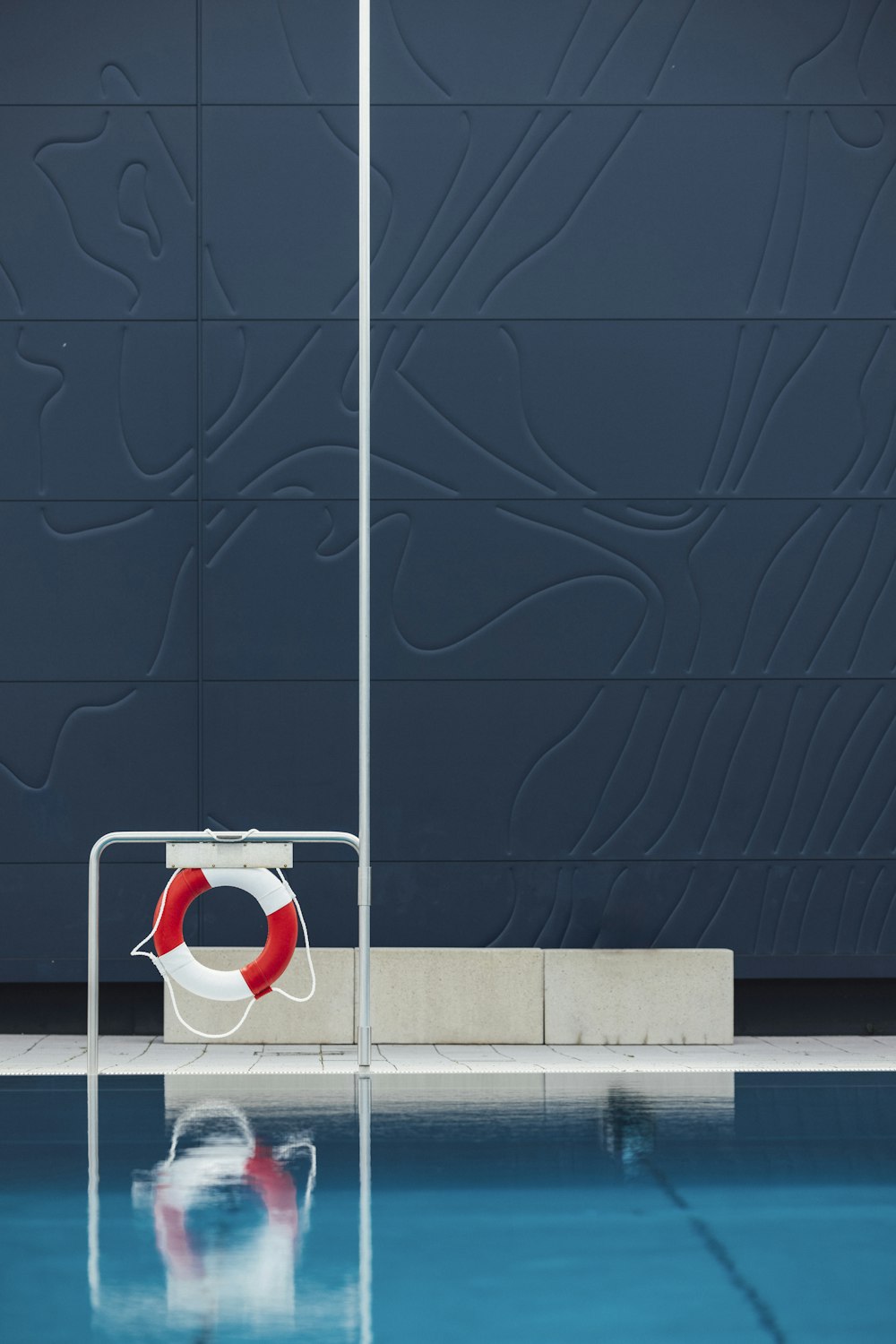 a red and white life preserver sitting on the side of a swimming pool