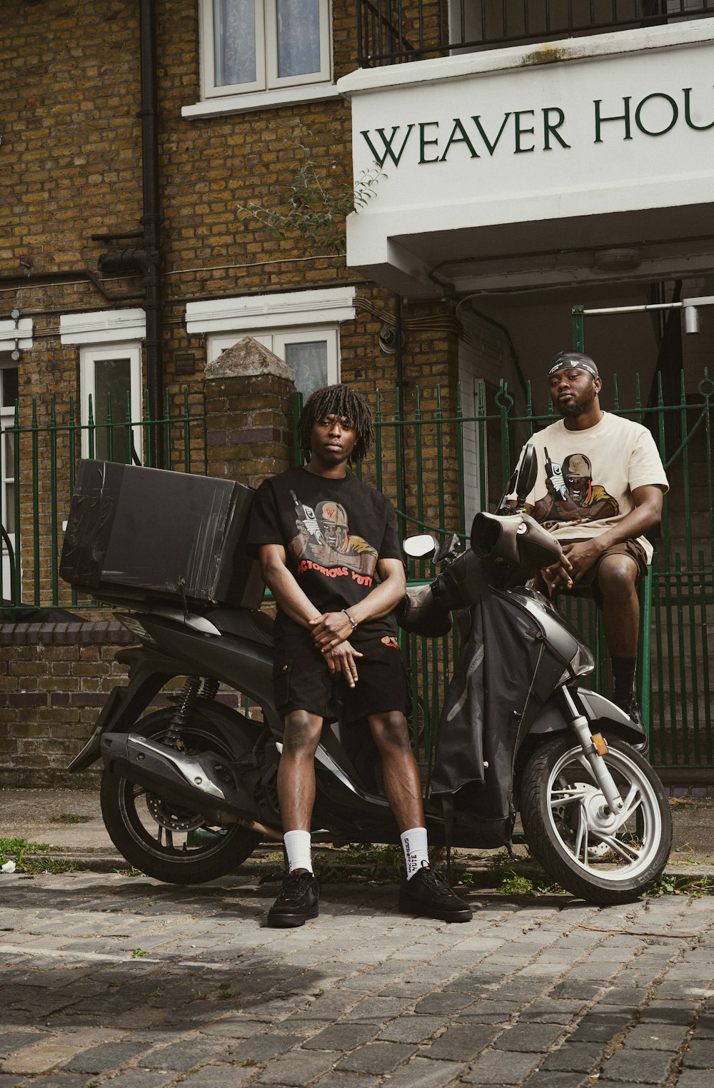 a man sitting on a motorcycle next to another man