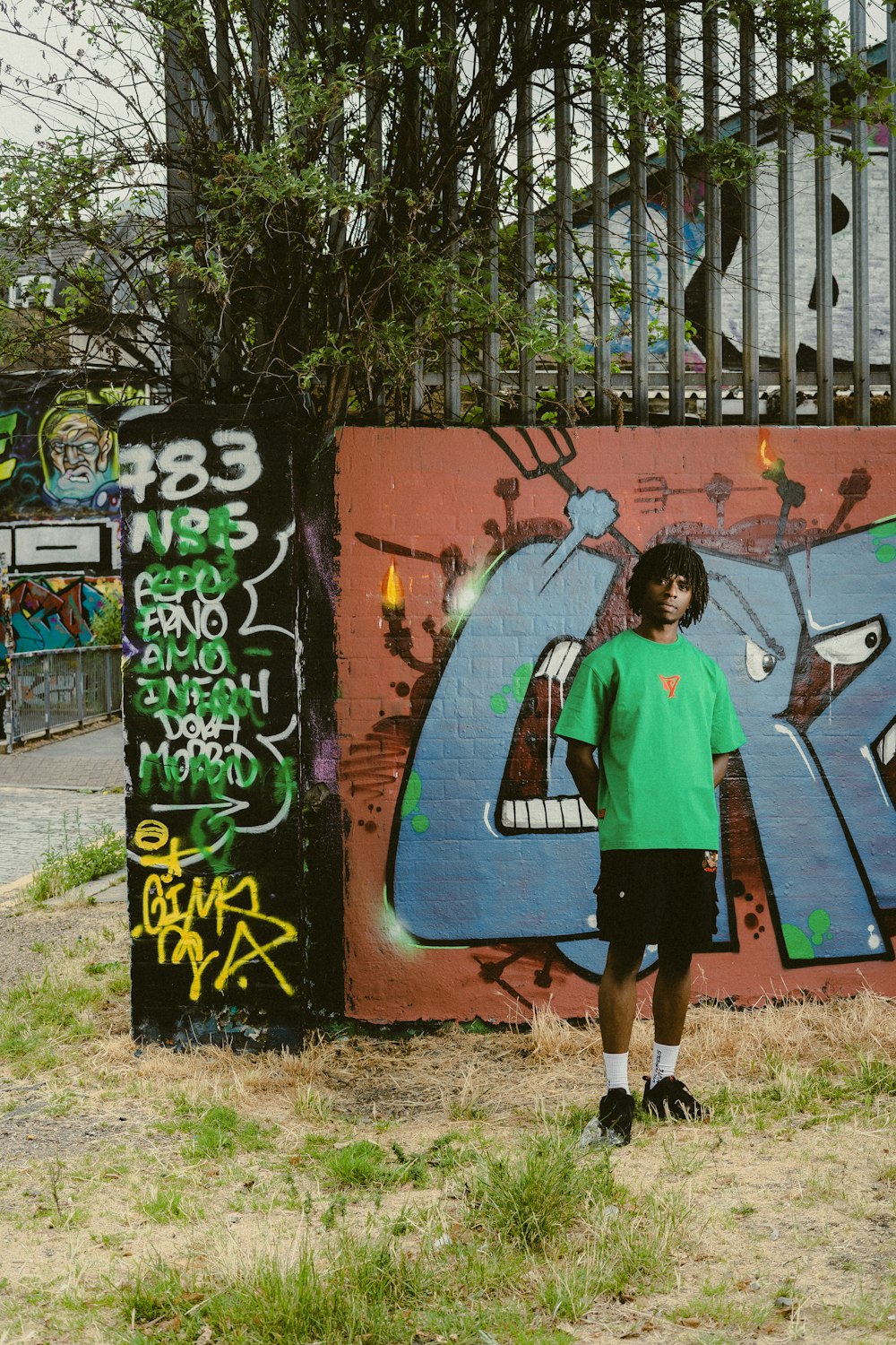 a young man standing in front of a graffiti covered wall