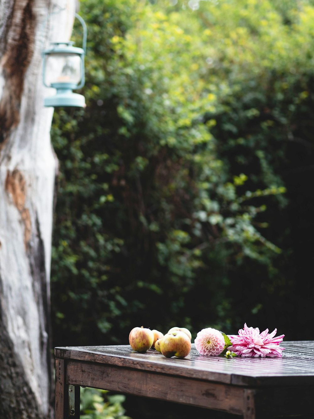 a wooden table with flowers and apples on it