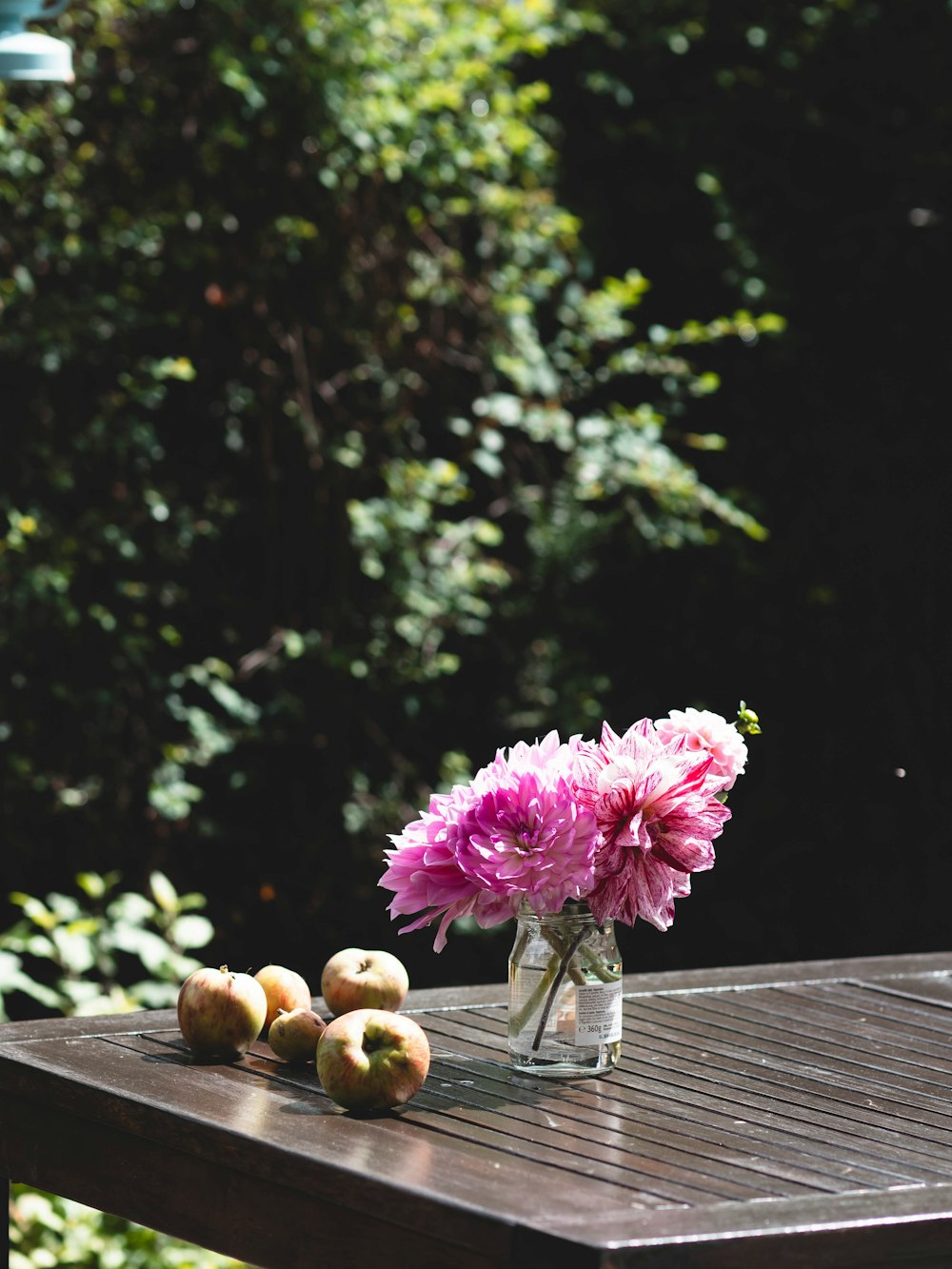 a glass vase filled with pink flowers sitting on top of a wooden table