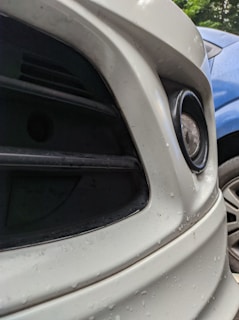 Close-up of a car's front bumper before repair, showing dents and scratches.
