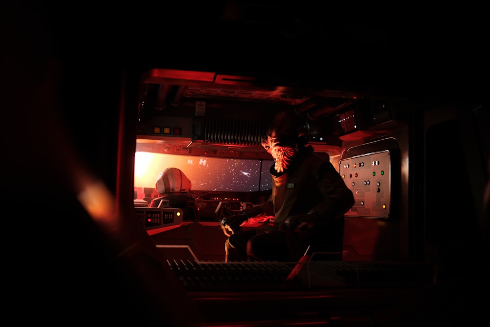 um homem sentado em frente a um monitor em uma sala escura