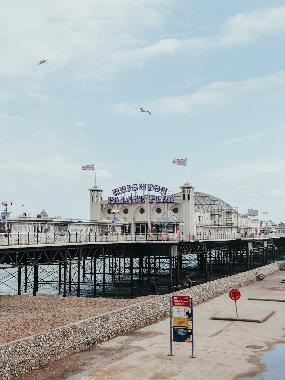 a pier with a few birds flying over it