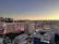 A cityscape view of Las Vegas at sunset, showcasing the skyline with prominent hotels and casinos. The sky displays a gradient of colors from dark blue to warm yellow as the sun sets in the background. Notable buildings are illuminated with lights, contributing to the vibrant nightlife atmosphere.