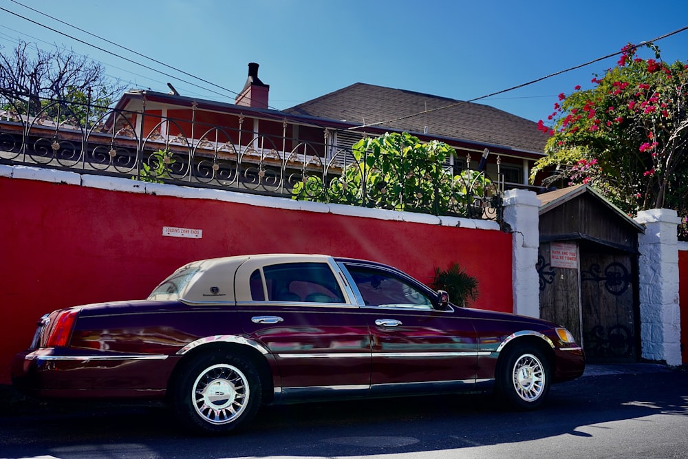 a maroon car parked in front of a red building