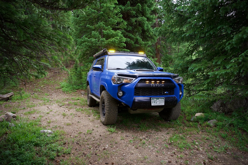 a blue truck parked in the middle of a forest