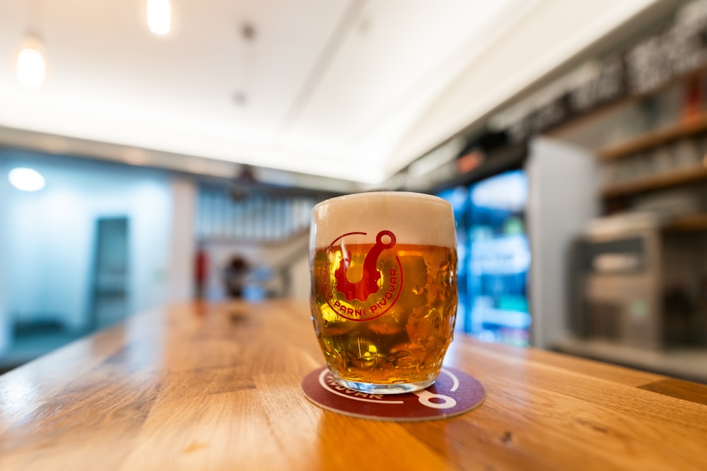 a glass of beer sitting on top of a wooden table