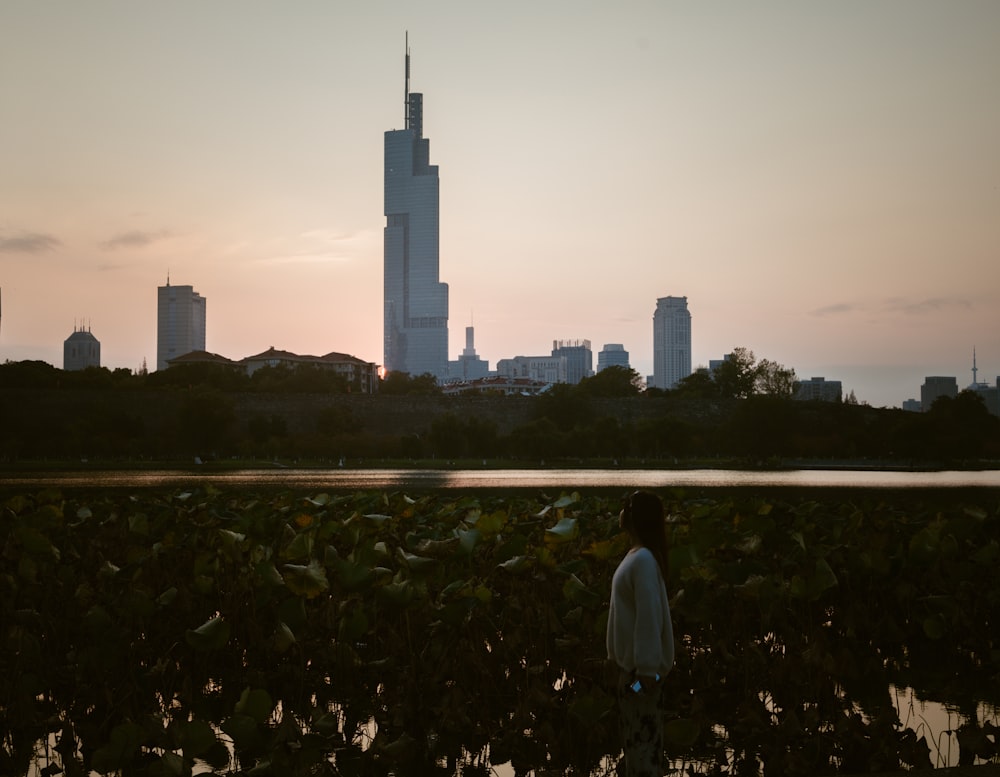 a person standing in front of a body of water with a city in the background