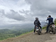 A group of riders pausing at a scenic overlook with rolling hills stretching into the distance.