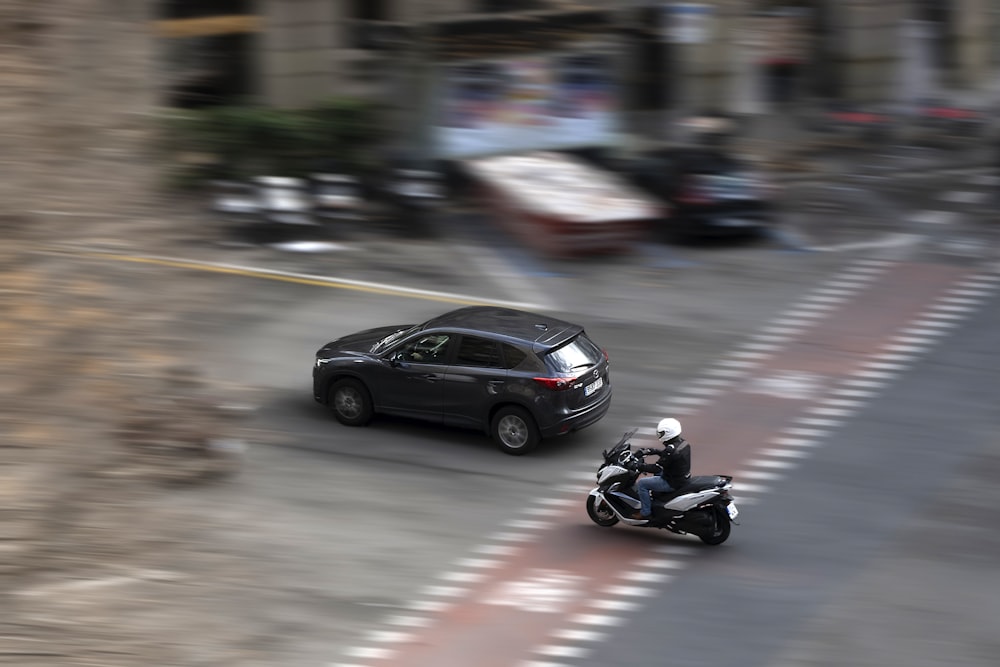 a car and a motorcycle driving down a street