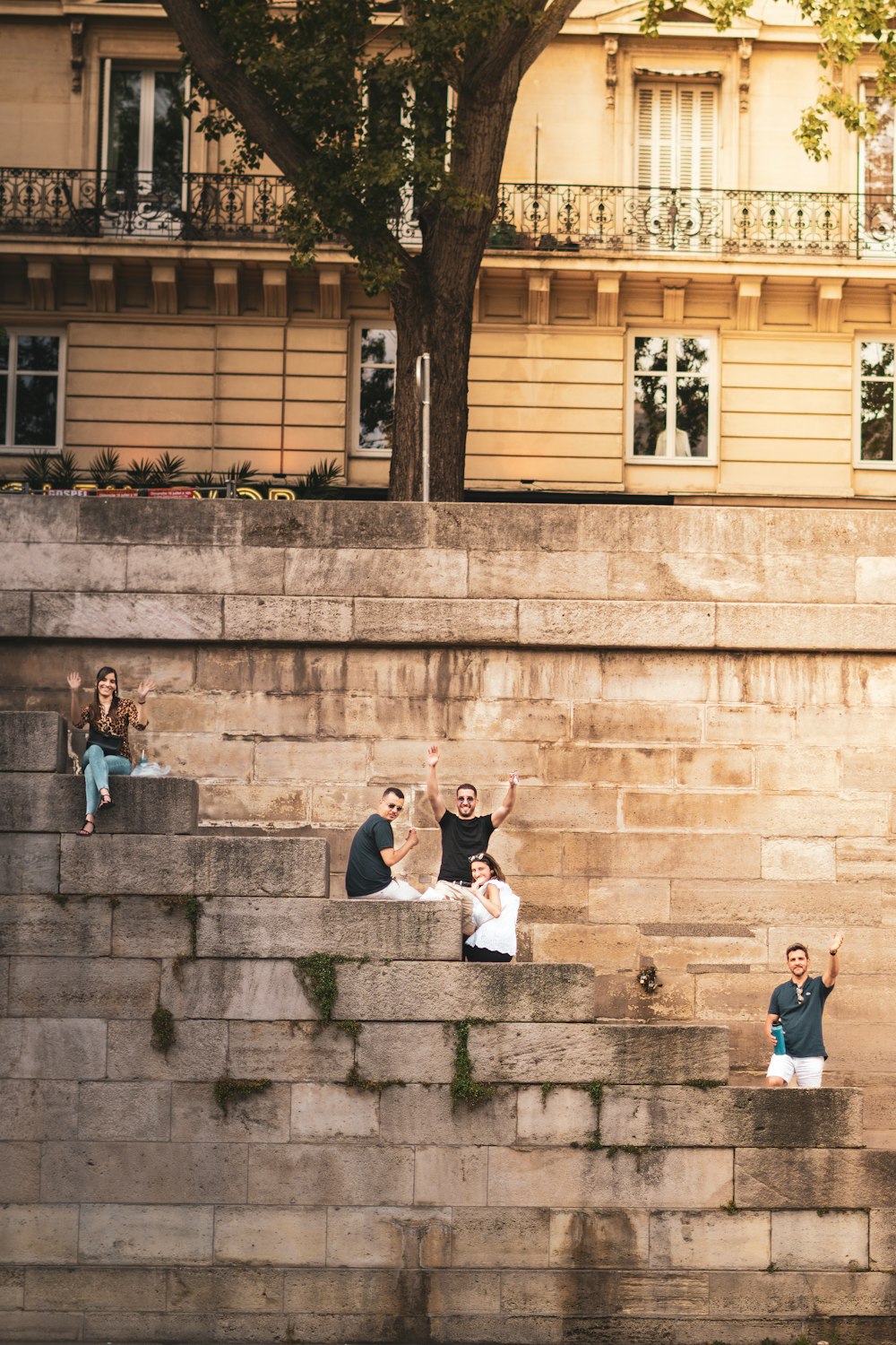 a group of people sitting on the side of a stone wall