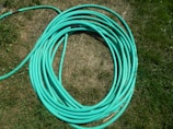 A close-up of a durable green irrigation hose coiled neatly on a farm field.