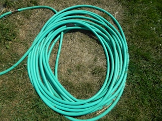 Green garden hose with brass insertion fittings coiled on grass.