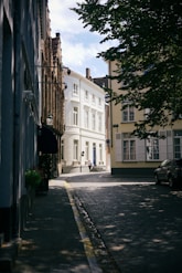 a narrow street with a white building in the background