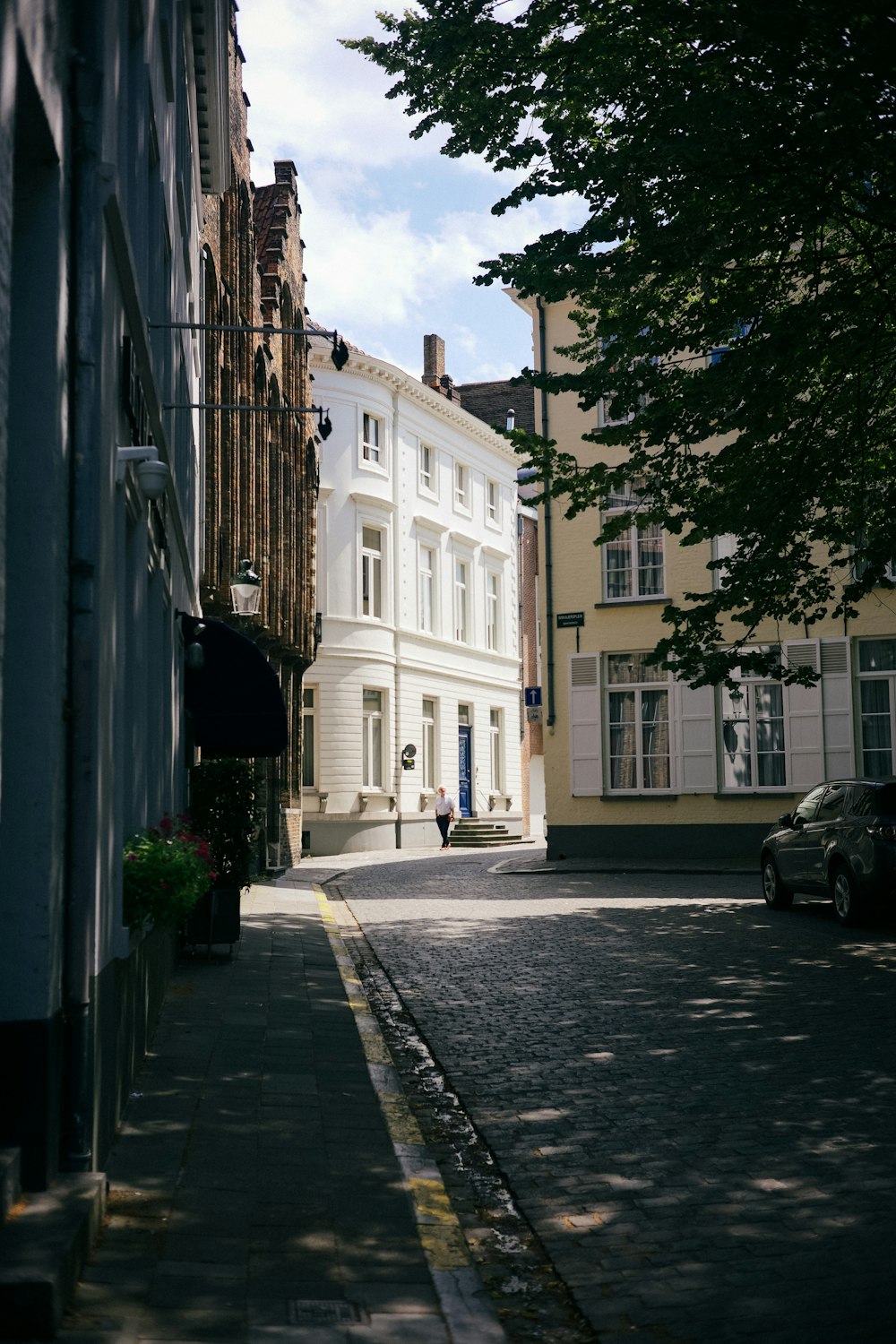a narrow street with a white building in the background