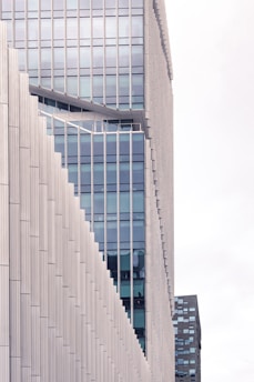 A modern high-rise building with a unique stepped architectural design featuring glass windows and beige paneling. The structure showcases a combination of vertical and diagonal lines, emphasizing a contemporary aesthetic.