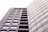 A modern, high-rise building with a sleek, rectangular design and numerous windows. The structure is composed of two distinct sections: one with visible balconies and another with a seamless glass facade. The lighting creates a soft, uniform tone across the building's exterior.