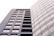 A modern, high-rise building with a sleek, rectangular design and numerous windows. The structure is composed of two distinct sections: one with visible balconies and another with a seamless glass facade. The lighting creates a soft, uniform tone across the building's exterior.