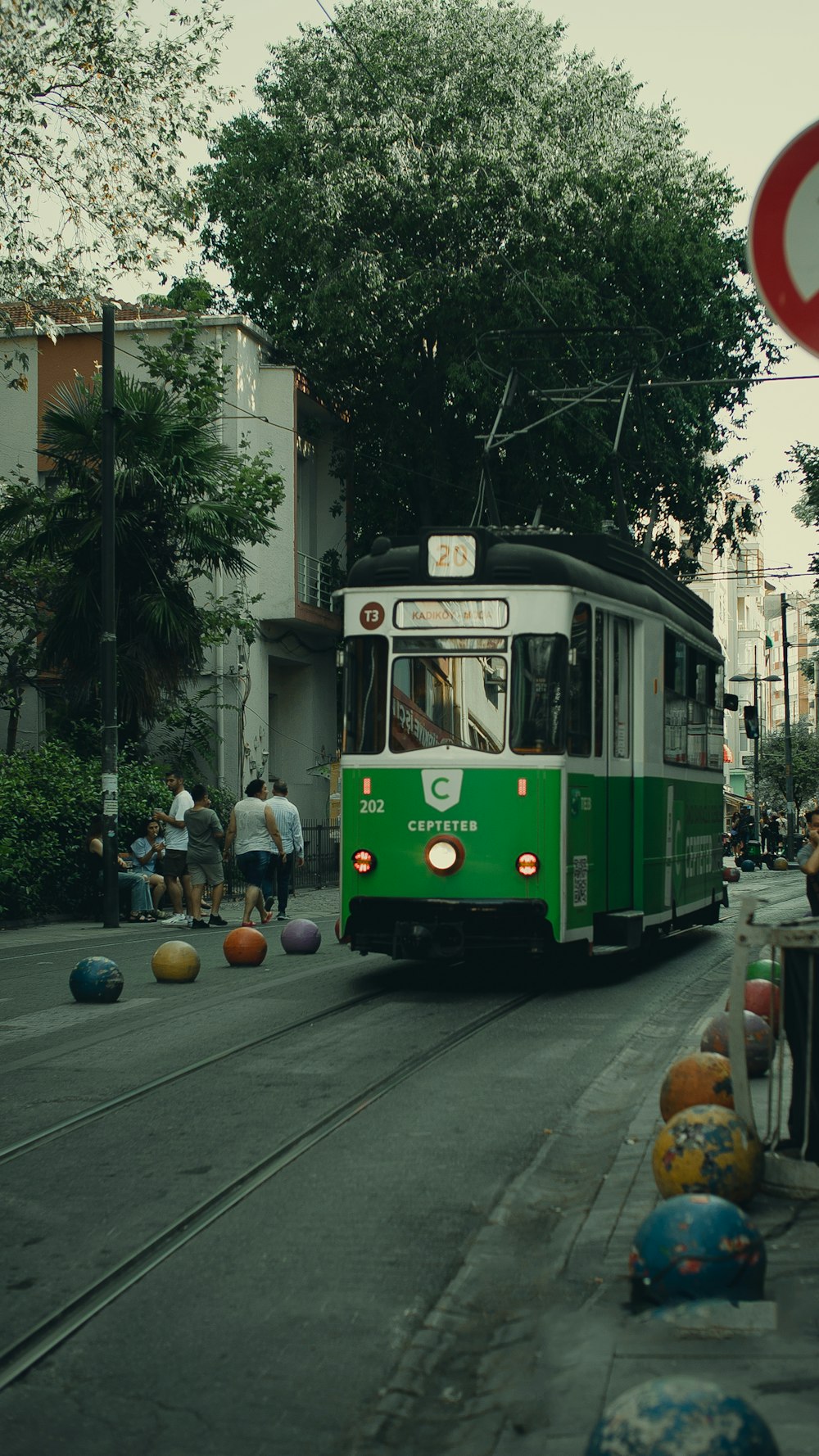 a green and white trolley driving down a street