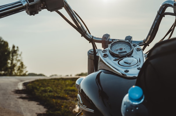 Close-up of a motorcycle’s dashboard with a scenic coastal view in the background.