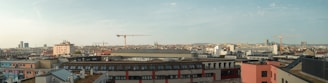 A panoramic view of a modern urban development with ongoing construction and cranes.