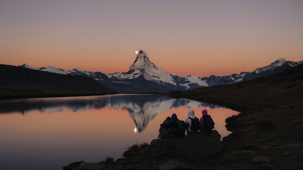 a group of people sitting next to a body of water