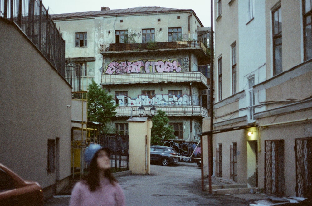 a woman walking down a street next to tall buildings