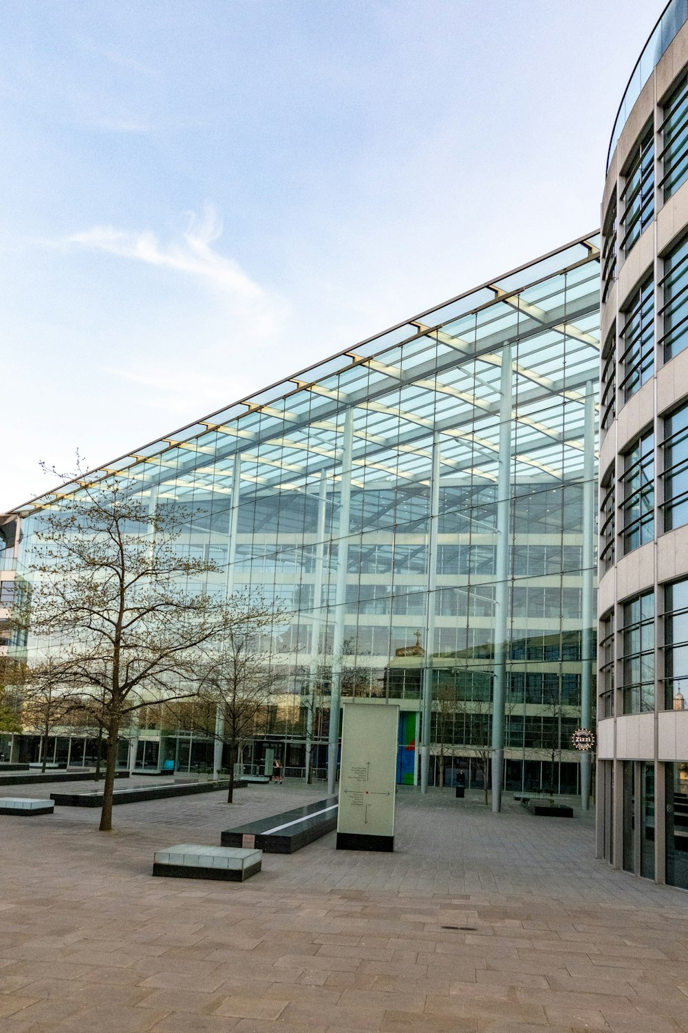 a large glass building with a tree in front of it