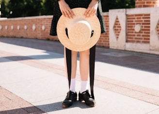 A customer wearing a stylish handmade hat outdoors on a breezy day.