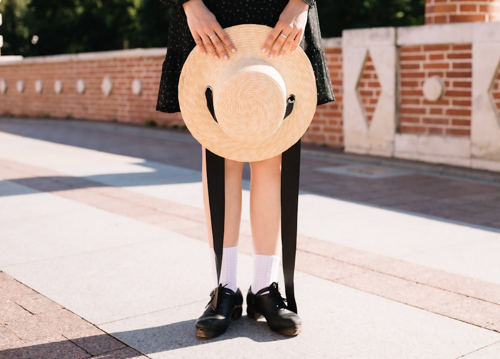 a woman in a black dress holding a straw hat