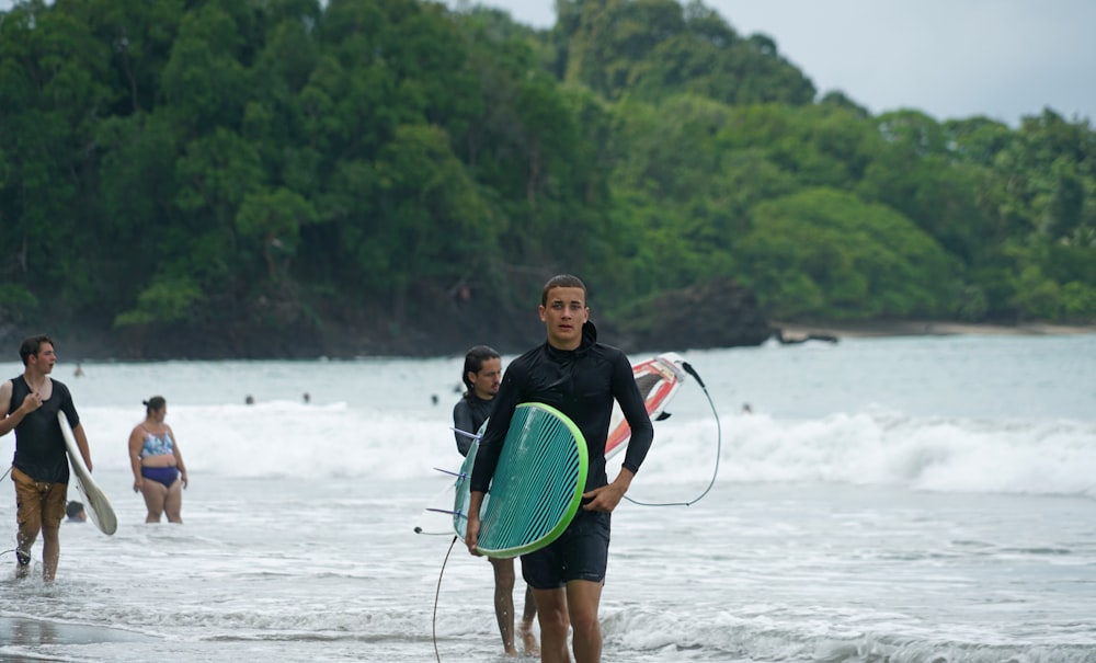 a group of surfers walking out of the ocean