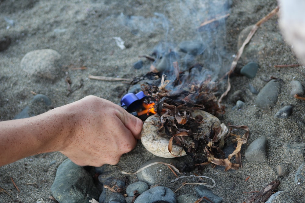 eine Person, die eine Flasche über einem Lagerfeuer hält