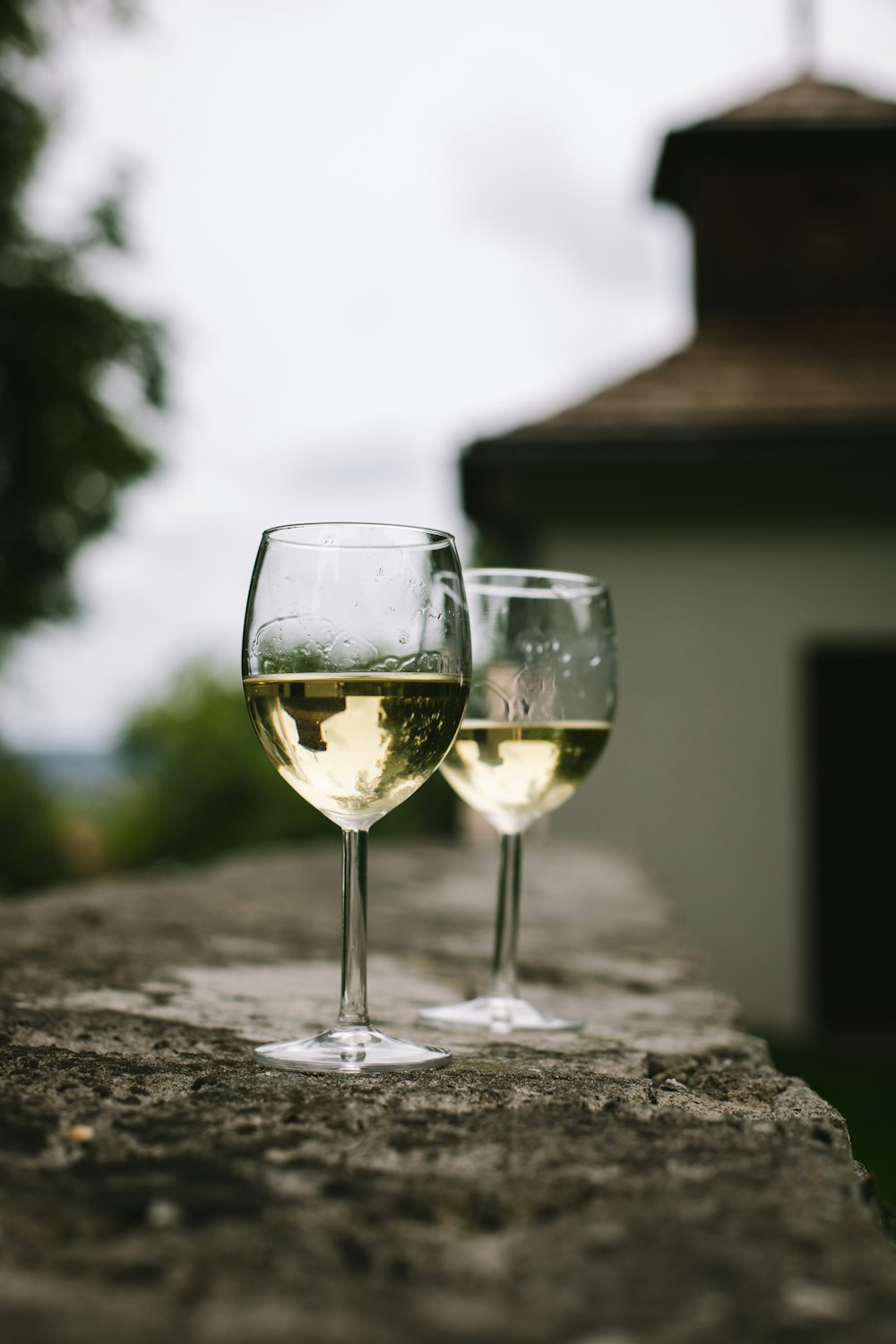 two glasses of wine are sitting on a ledge