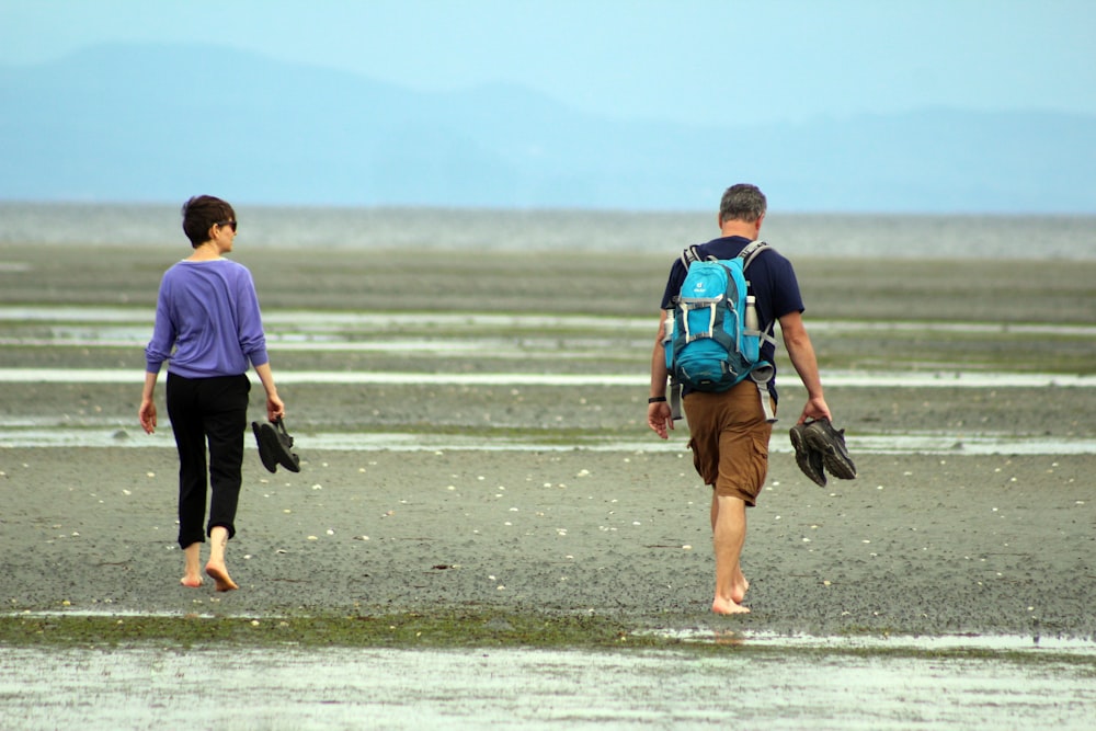 a couple of people walking across a wet field