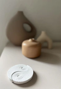 A series of minimalist ceramic pieces arranged in a grid, showcasing varied textures in monochrome tones.