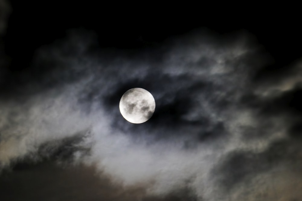 Une pleine lune est vue à travers un ciel nuageux