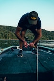 Close-up of hands tying fishing knots with precision on a calm riverbank.