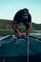 Close-up of hands tying fishing line by a calm river
