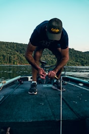 A fishing buddy helping another untangle a fishing line on a boat.
