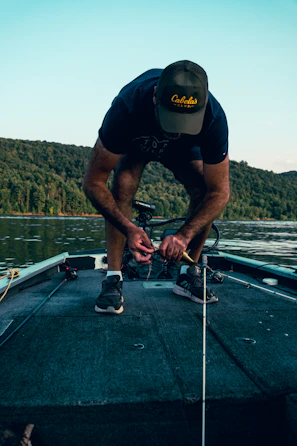 Close-up of hands tying fishing line by a calm river
