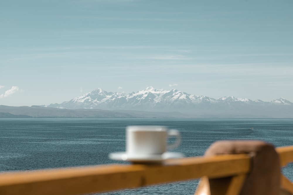 a cup of coffee sitting on top of a wooden railing