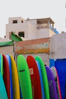 A row of colorful surfboards leaning against a rustic wooden wall in the workshop.