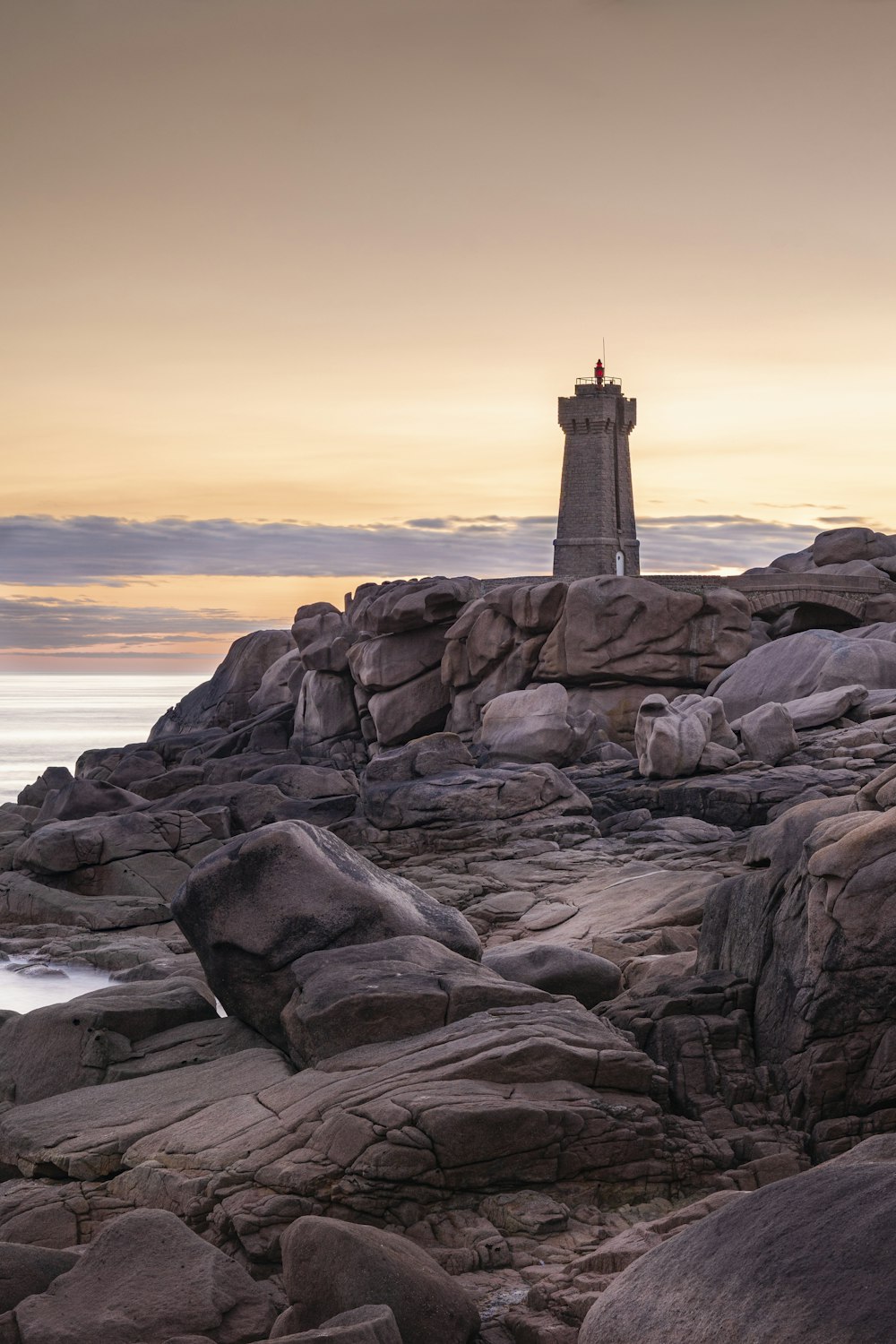 a lighthouse on a rocky shore with a body of water in the background