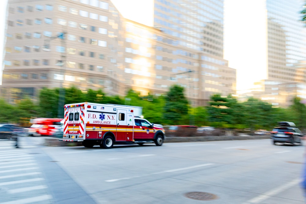 Ein Krankenwagen, der neben hohen Gebäuden eine Straße in der Stadt entlangfährt